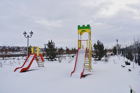 The children's slide in the park is covered with the first snow.