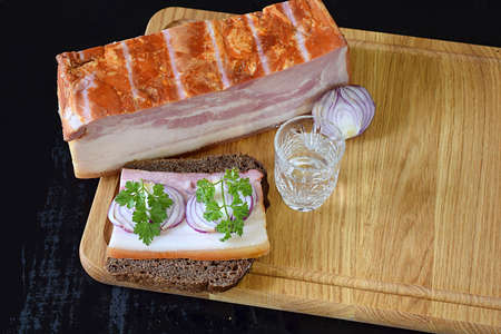 A piece of brisket, a brisket and onion sandwich and a glass of vodka.の写真素材