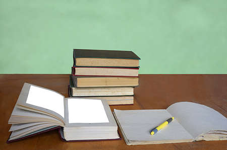 A stack of books, a pen and a notebook on the table.