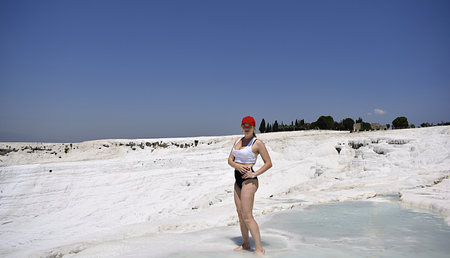 Young woman on the slope of a mountain covered with white travertine (Pamukkale)の写真素材