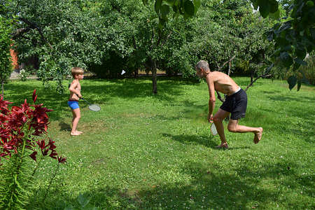Grandfather and grandson play badminton in the garden.の写真素材