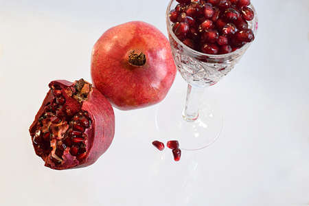 Pomegranate fruits and pomegranate seeds in a glass on a white background.の写真素材