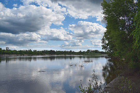 A river with populated banks and a sky with cumulus clouds.