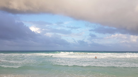 Lonely swimmer in the ocean with big waves in pre-storm weather.の写真素材