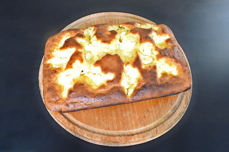 A cottage cheese pie on a wooden tray placed on a black table.の写真素材