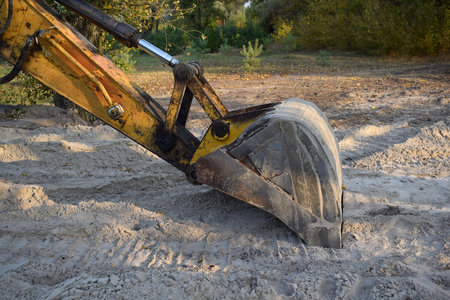 An excavator bucket lies on a sandy surface close-up.の写真素材