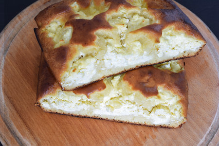 A cottage cheese pie on a wooden tray placed on a black table.の写真素材