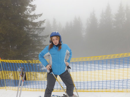 A person in blue ski gear poses on a snowy mountain slope.の写真素材