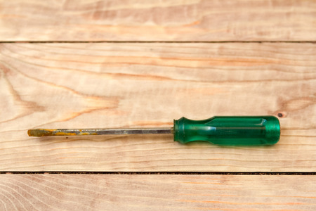 old rusty screwdriver with green handle on the tableの写真素材