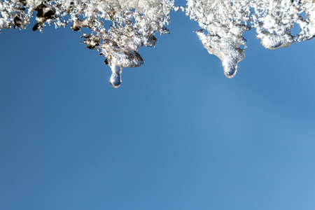 Beautiful openwork icicles on blue sky background