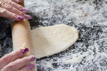Rolling the dough with a rolling pin on the table