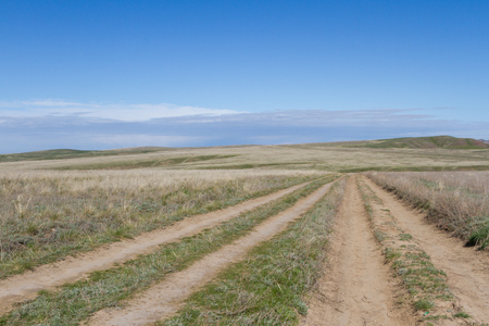 Kazakhstan steppe with rolling dirt roads among the hillsの写真素材