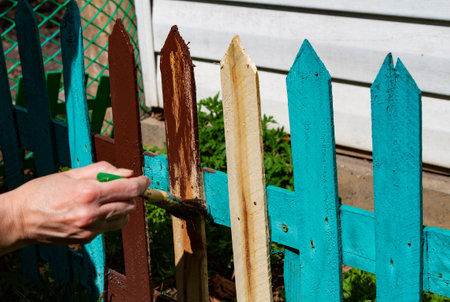 painting a picket fence brown by a woman's handの写真素材