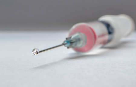 Drop on syringe needle filled with red medicamentの写真素材