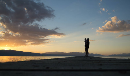 Silhouette of father and daughter on sunset by the lakeの写真素材
