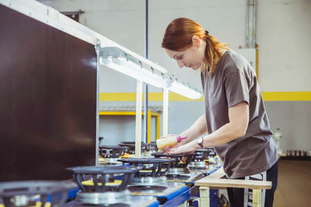 Bila Tserkva, Ukraine, March 2021: woman worker glues a music speaker at a factory