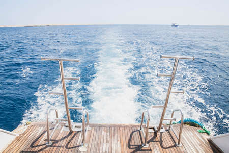 white waves from the ship engine and brown boards of the stern of the ship