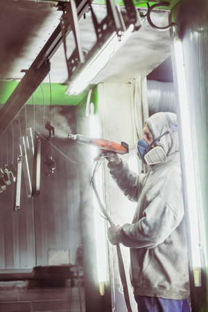 Bila Tserkva, Ukraine, March 2021: Worker paints metal parts in a factory