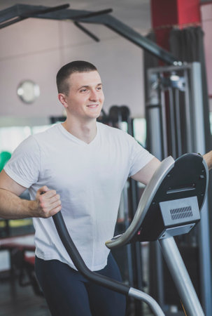 athlete works out on the simulator in the fitness club and smiles
