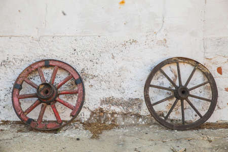 Rotten wooden wheels near the shabby barn wallの写真素材