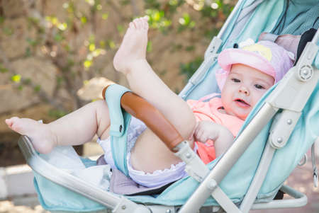 charming newborn baby girl in blue baby carriageの写真素材