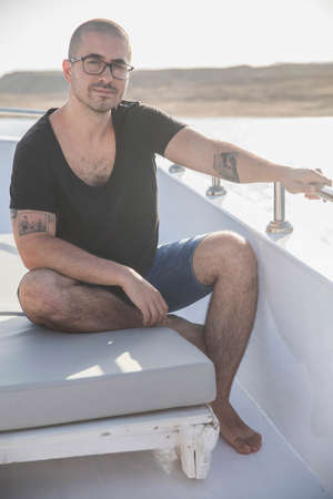 attractive guy with glasses resting on a yachtの写真素材