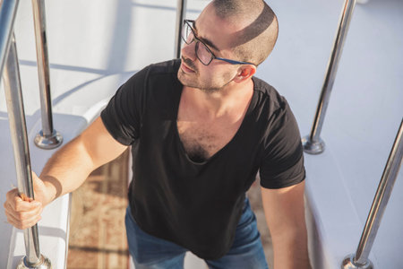 attractive guy climbs the stairs on the yachtの写真素材