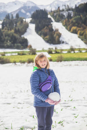 blonde girl makes a snowman in Slovenia in the Alpsの写真素材