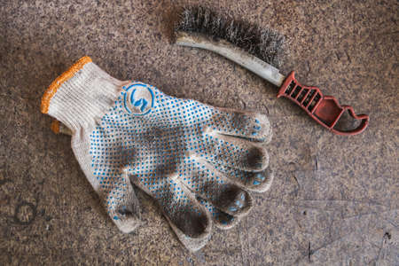 old dirty gloves and metal brush lie on the table in the workshopの写真素材