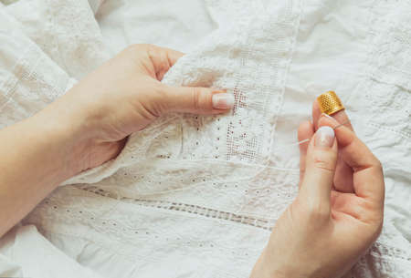 Woman sews a dress. Hands with a needle and thimble close upの写真素材