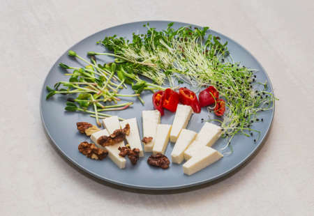Cheese, chili peppers, walnut and micro greens on a gray plateの写真素材