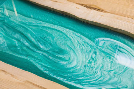 liquid turquoise epoxy on the kitchen table in the workshopの写真素材
