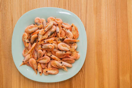 Blue plate with shrimps on a wooden table