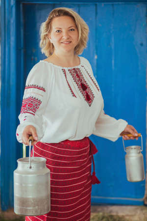 Hostess in embroidered clothes with milk can. Retro photo of ancient Ukrainian lifeの写真素材