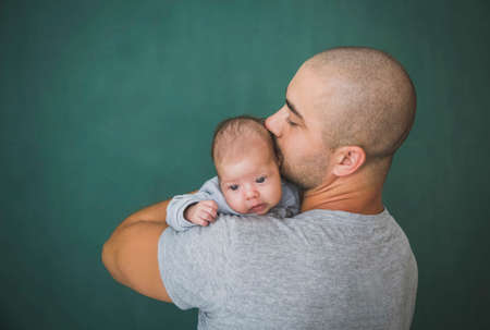 Young father with short hair kisses his newborn daughter