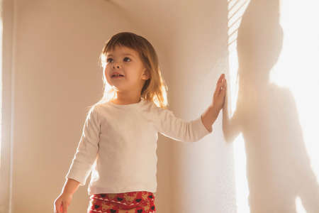 charming beautiful girl plays with her shadow