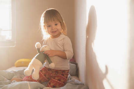 charming blonde baby with a toy in the morningの写真素材