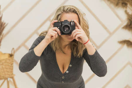 Attractive girl with neckline taking aim by old cameraの写真素材