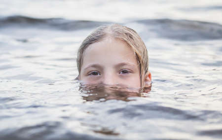 teenager girl bathes in a river and only half of her face is visibleの写真素材