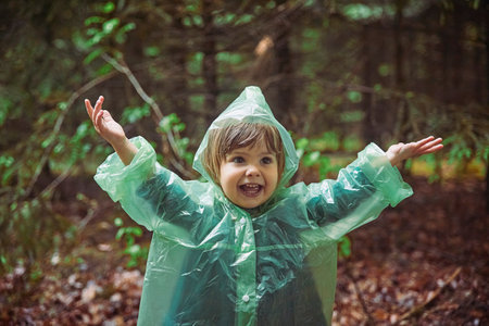 Charming child in raincoat in the evening forest in Denmarkの写真素材