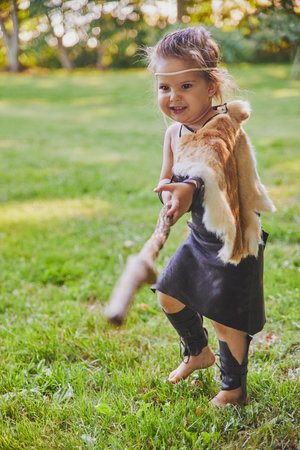 Cute baby dressed in the clothes of primitive people with combat staffの写真素材