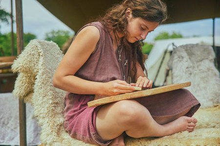Hojbjerg, Denmark, August, 2022: Girl carving wood at viking festivalのeditorial素材