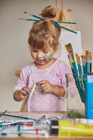 Charming dirty child draws at home with acrylicsの写真素材