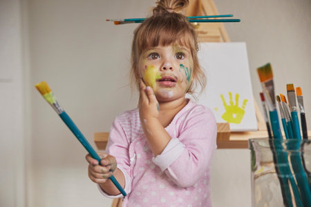 Charming child draws and stains everything with paintsの写真素材