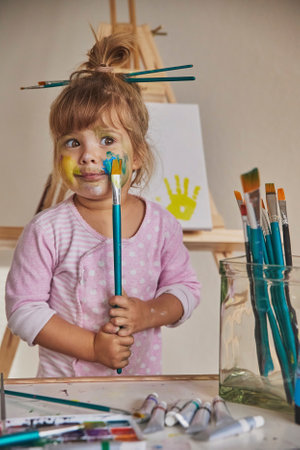 Charming child draws and stains everything with paintsの写真素材