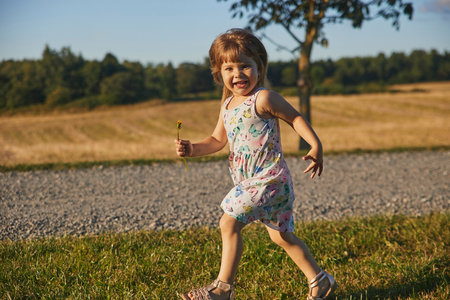 charming child in a sundress running down the street in the suburbsの写真素材