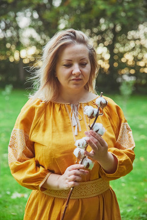 beautiful Ukrainian woman in embroidered dress holds a sprig of cottonの写真素材