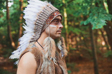 A man in traditional Native American clothing in the evening forestの写真素材