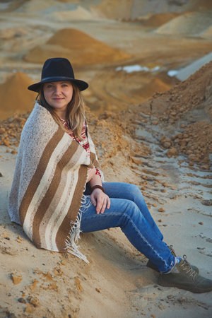 Beautiful woman in a hat with a plaid near a quarry at sunsetの写真素材