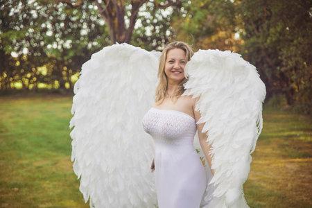 Beautiful woman dressed as an angel in the evening gardenの写真素材